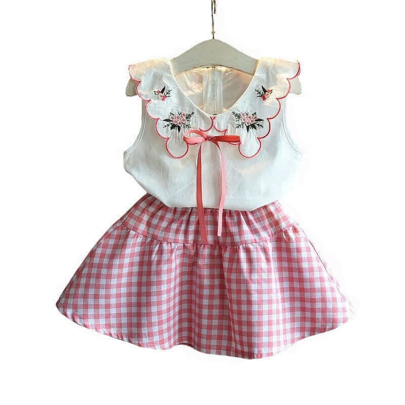 Pink and white floral embroidered dress with gingham skirt for girls on a hanger.