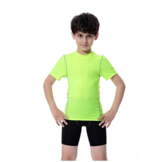 Young boy in a bright green sport t-shirt and black shorts posing confidently against a white background.